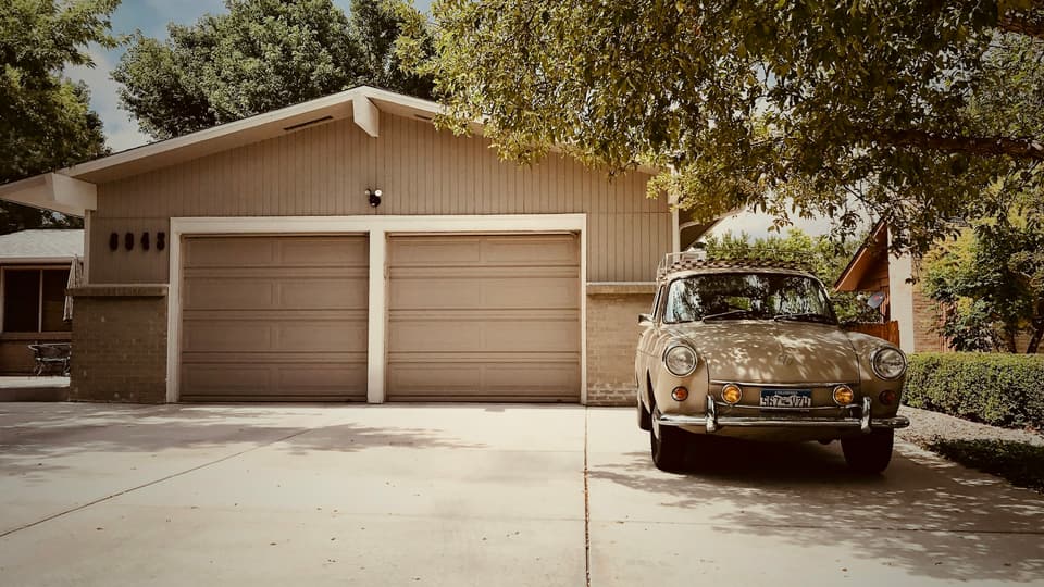 A ranch-style house with two single garage doors and a classic car in the driveway